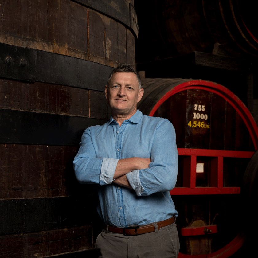 Andrew Baldwin, Penfolds Red Winemaker, stands in front of large wine barrels
