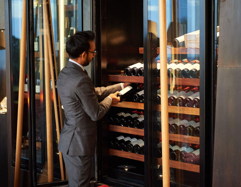 Sommelier at Magill Estate Restaurant choosing a wine from the cellar