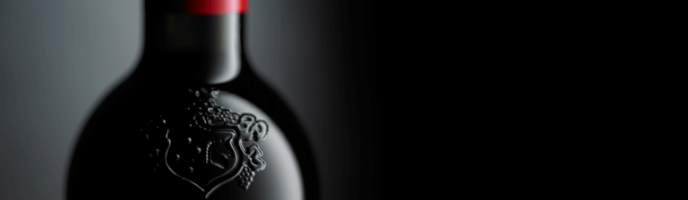 Close up of a neck of a Penfolds bottle. Embossed crest is visible on glass and Penfolds red capsule