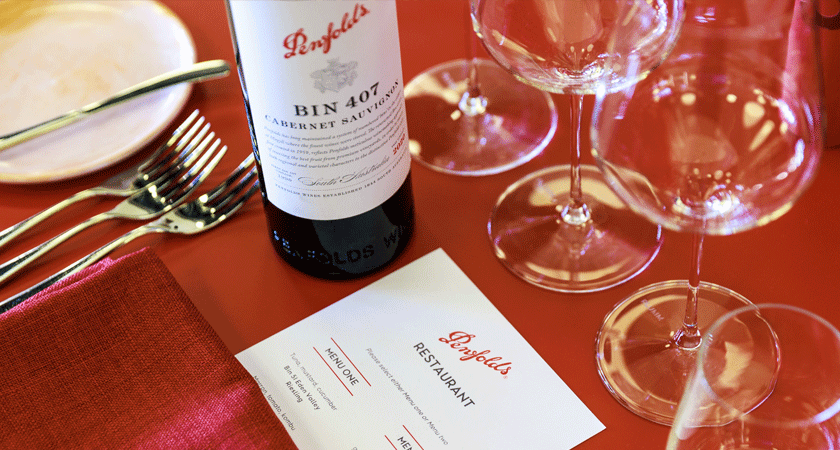 Bin 407 Cabernet bottle and Penfolds menu card sits on red table