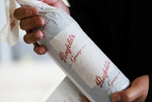 Person holds tissue paper wrapped wine bottle