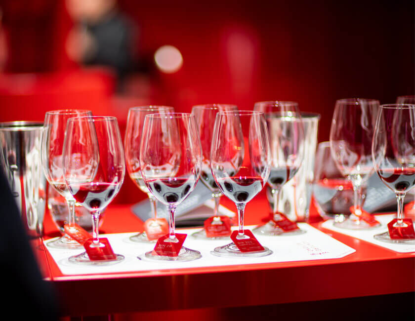 Six wine glasses on a white placemat on a red table