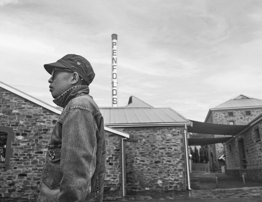 Black and white photo. Nigo stands in front of heritage brick building and Penfolds Magill Estate.
