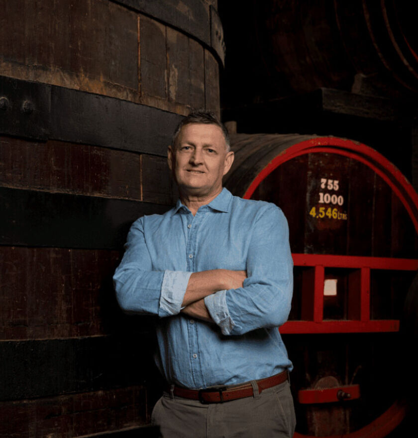 Andrew Baldwin, Penfolds Red Winemaker, stands in front of large wine barrels