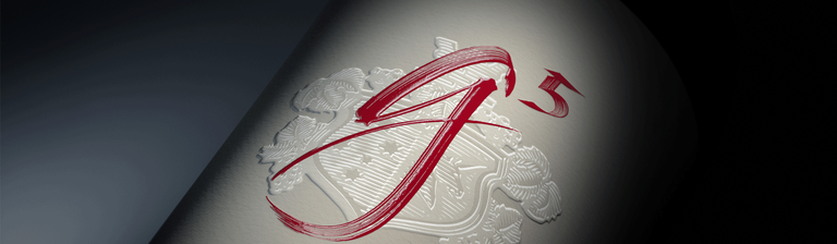 Close up of Penfolds g5 label.  A red calligraphy script 'g' and a '5' over a beige embossed logo on a darker beige label