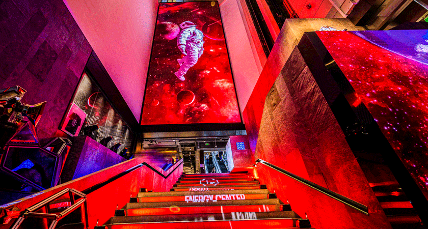Entrance to Venture by Penfolds Shanghai.  Neon lights lead up the stairs.  Astronaut graphic appears on screen above 