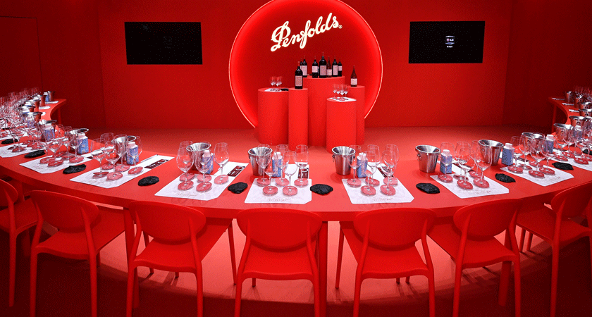 The red masterclass room of the event.  A semi circle red table faces inwards towards bottles on a pedestal 