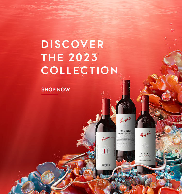 Three Penfolds bottles surrounded by coral against a red underwater background.