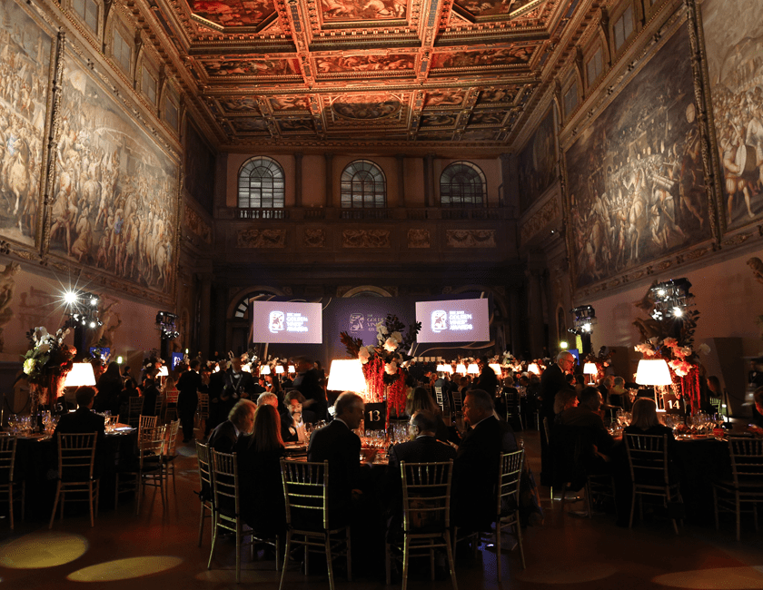 Black tie dinner in large hall with high ceilings covered in historic paintings