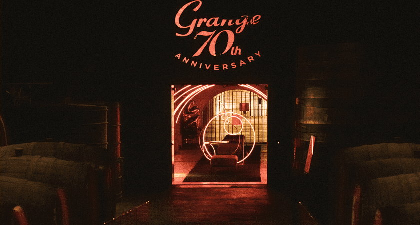 Grange 70th Anniversary Red Neon logo appears above red lit doorway to a tunnel 