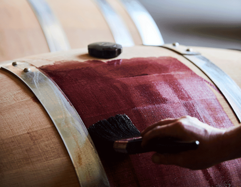 Close up of barrel being painted with lees, giving it a rich purple colour