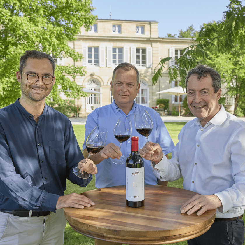 Penfolds and Dourthe Winemaker cheers with a glass of wine outside with Chateaux building behind