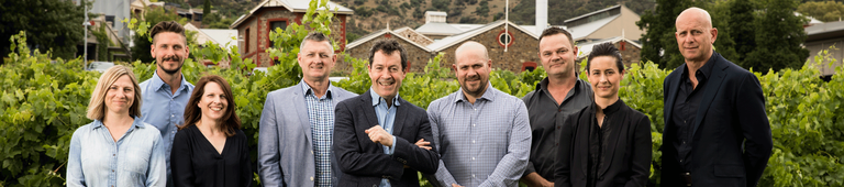 Penfolds winemaking team on the lawns of Magill Estate winery. Vineyards appear hehind them